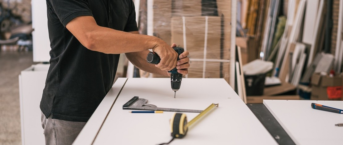 Eine Person mit einer Bohrmaschine am Werken; gesunde und sichere Arbeit gestalten im Handwerk