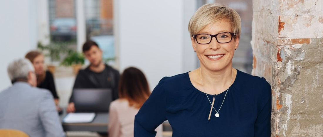 Eine Frau in mittlerem Alter im Büro - Wechseljahre und Menopause beeinflussen die Arbeitsfähigkeit.