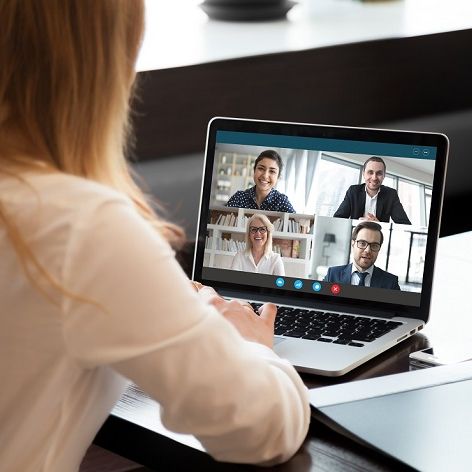 Eine junge Frau sitzt am Laptop und hält mit weiteren vier Personen eine Videokonferenz ab.