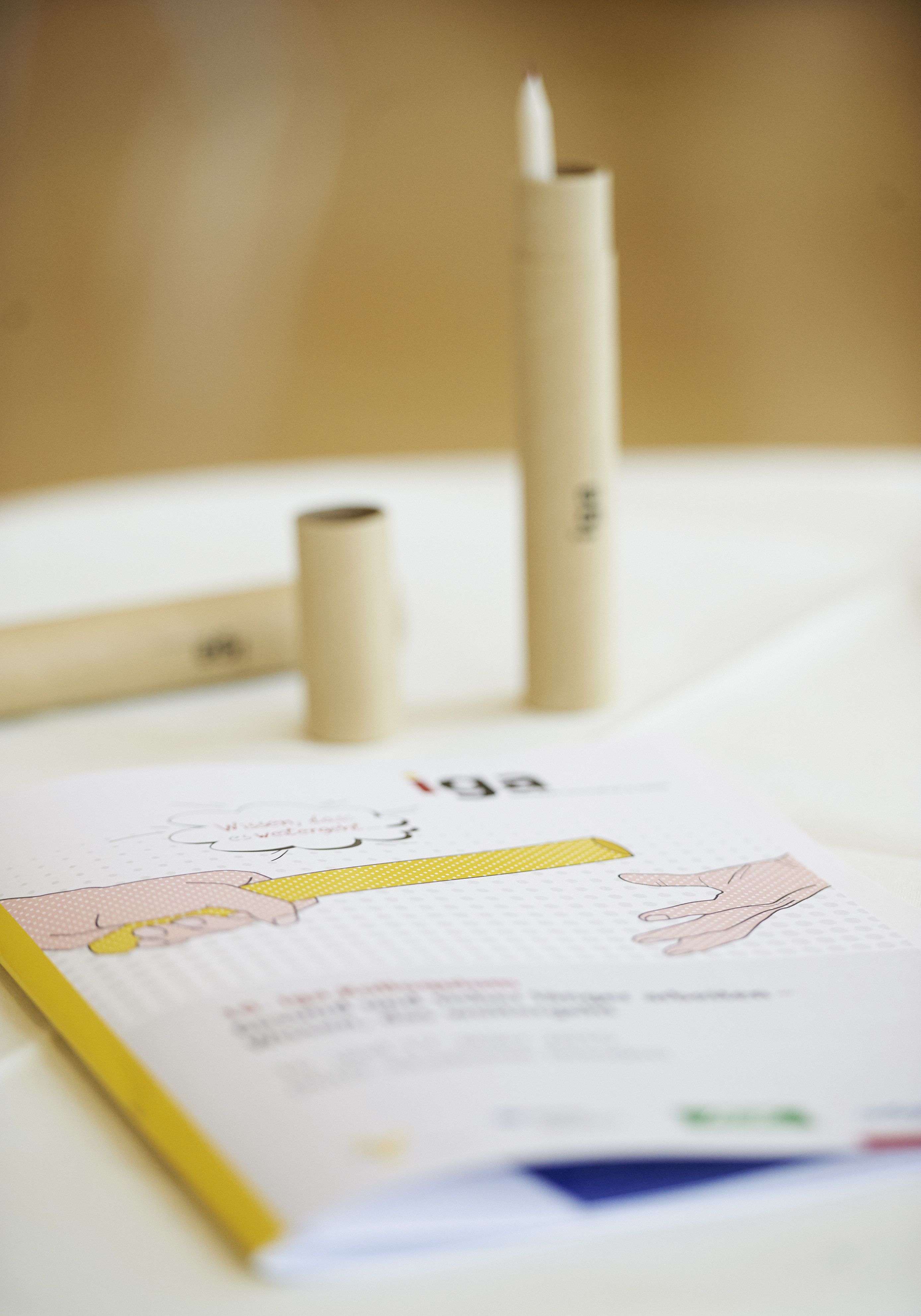 iga.Kolloquium 2015: Auf einem Tisch liegt das Programm, dahinter steht eine Stiftbox in Form eines Staffelstabes.