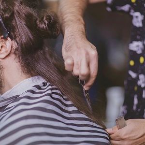 Ein Friseur schneidet einem Mann die Haarspitzen.